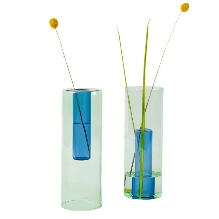 Two large reversible green and blue vases with dried flowers inside on a white background.