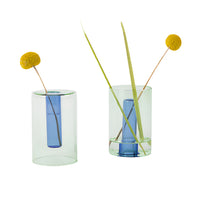 A small blue and yellow reversible glass vase containing some flowers and decorative elements.