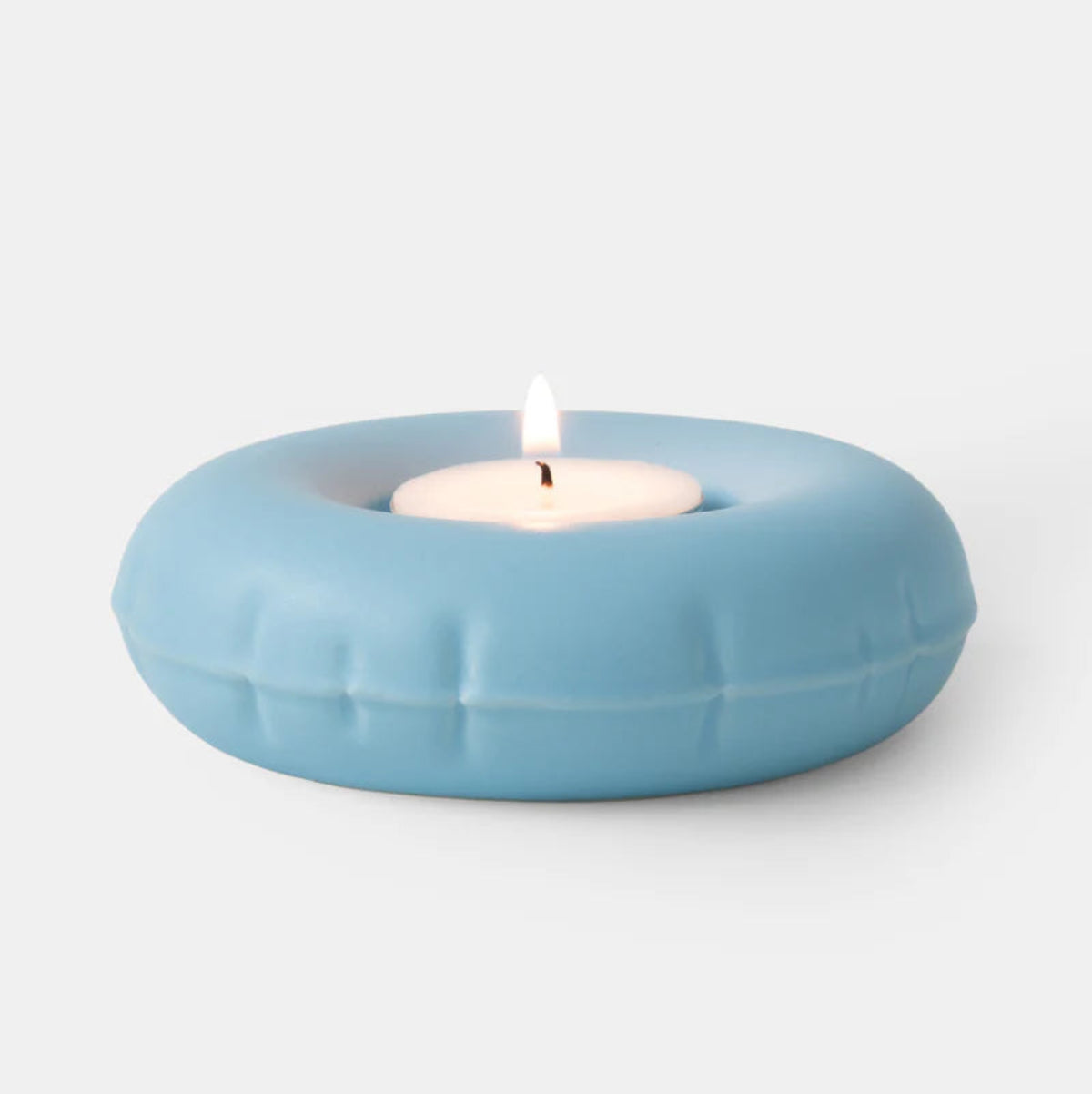 Light blue ceramic candle holder with a lit white candle on a light gray background