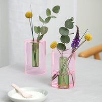Two small reversible glass vases displayed with flowers arranged in them.