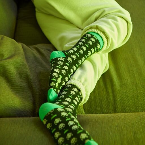 A person wearing black and green game design socks on a green sofa.