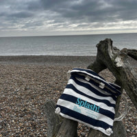 lifestyle picture of Splash! Bag on dry branches by pebbly beach on a cloud day