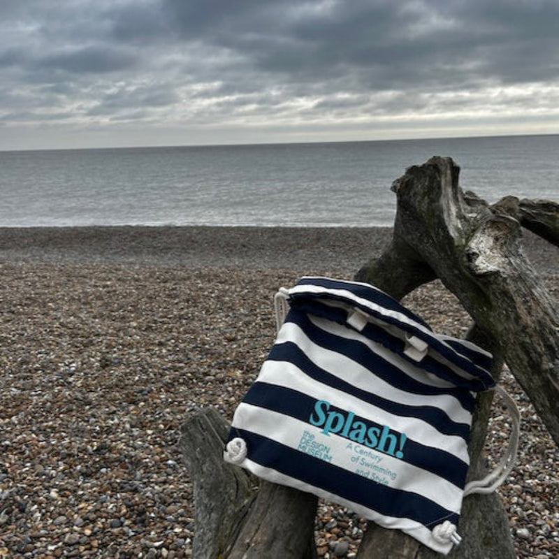 lifestyle picture of Splash! Bag on dry branches by pebbly beach on a cloud day
