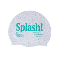 picture of swimming cap made from recycled materials of which has grey colour dots over white material, the swimming cap features the design museum logo and the exhibition logo "Splash! A Century of Swimming and Style", picture on a white background