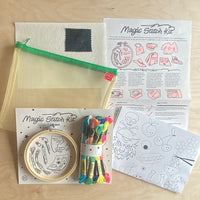 The contents of a magic stitch kit on a table, inclusing instructions, designs, thread and an embroidery hoop.