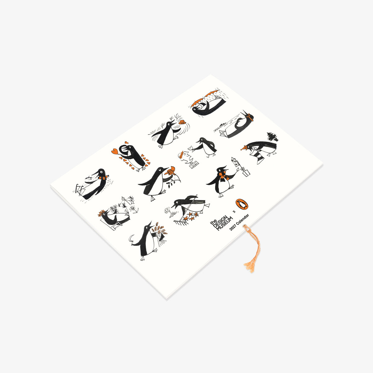 A white rectangular notebook or journal with a decorative cover featuring black and orange penguin illustrations, photographed on a light gray background.