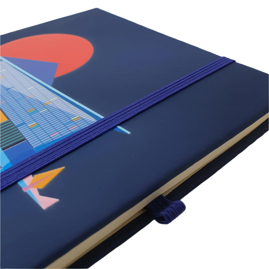 Close up image of the Design Museum Branded A5 size notebook front cover to detail its elastic bands to keep notebook closed and elastic band slot for a pen or pencil.