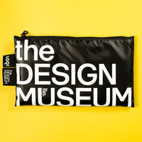A black zippered pouch with bold white text reading 'the DESIGN MUSEUM' on a bright yellow background. A small side tag shows the brand 'don' and 'the design museum'.