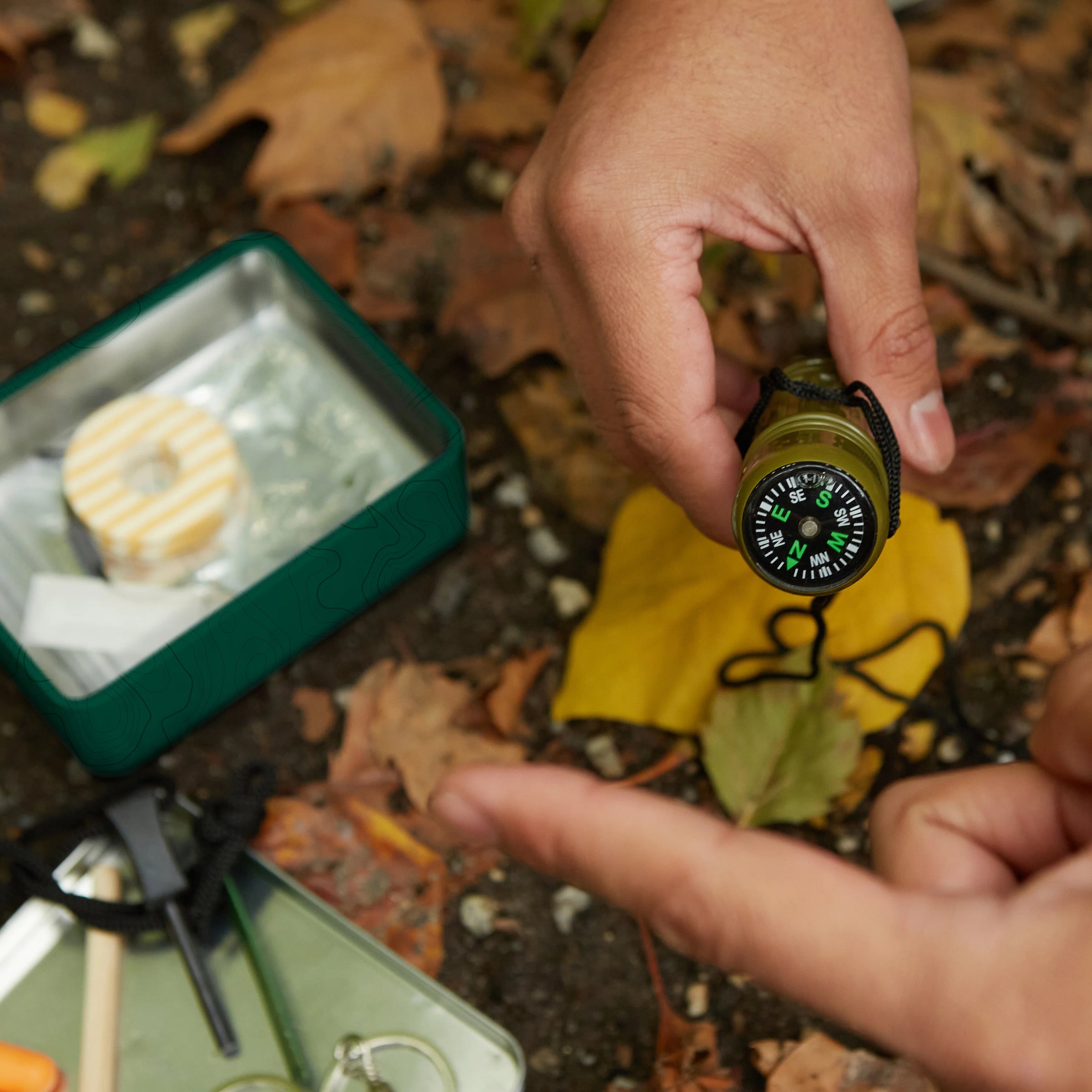 Person holding a compass with a camping scene in the background