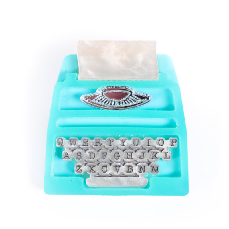 Turquoise typewriter-shaped tape dispenser on a white background