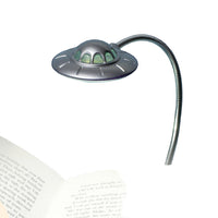 UFO-shaped book light clipped to a book