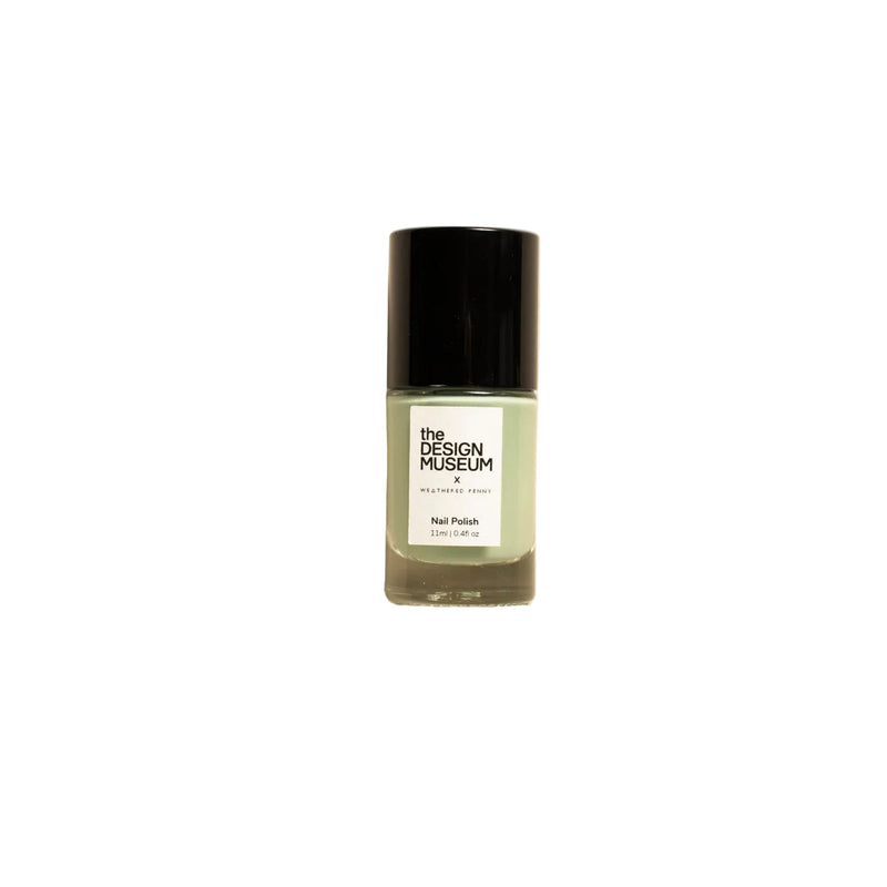 A bottle of nail polish by The Design Museum in sage green with a black cap, centered on a warm beige background.