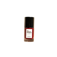 A bottle of nail polish with a black cap and a red label reading 'The Design Museum' and 'Nail Polish', centered on a warm off-white background.