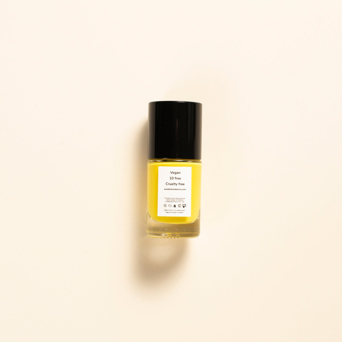 A small clear bottle filled with yellow liquid, topped with a black cap and labeled 'Golden Glow' by The Beauty Brand, centered on a warm off-white background.