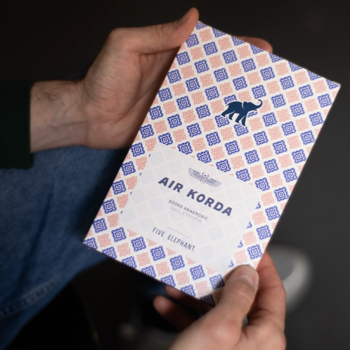 Hand holding a patterned box labeled 'Air Korda' with a logo.