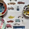 Collection of illustrated vehicles on a white surface with paint palettes and a brush.