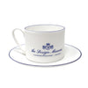 White teacup and saucer with blue text and design on a white background