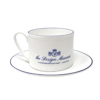 White teacup and saucer with blue text and design on a white background