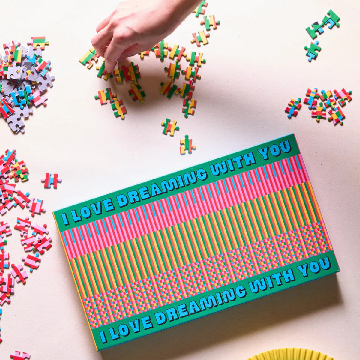 Colourful puzzle box with 'I love dreaming with you' text, surrounded by scattered puzzle pieces on a light surface.