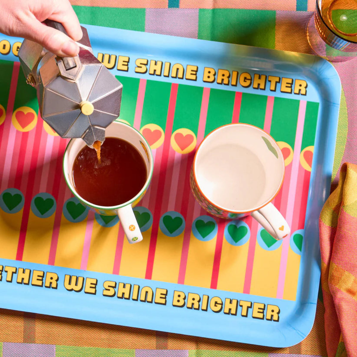 Person pouring coffee into a cup on a colourful tray with motivational text.