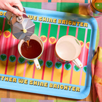 Person pouring coffee into a cup on a colourful tray with motivational text.