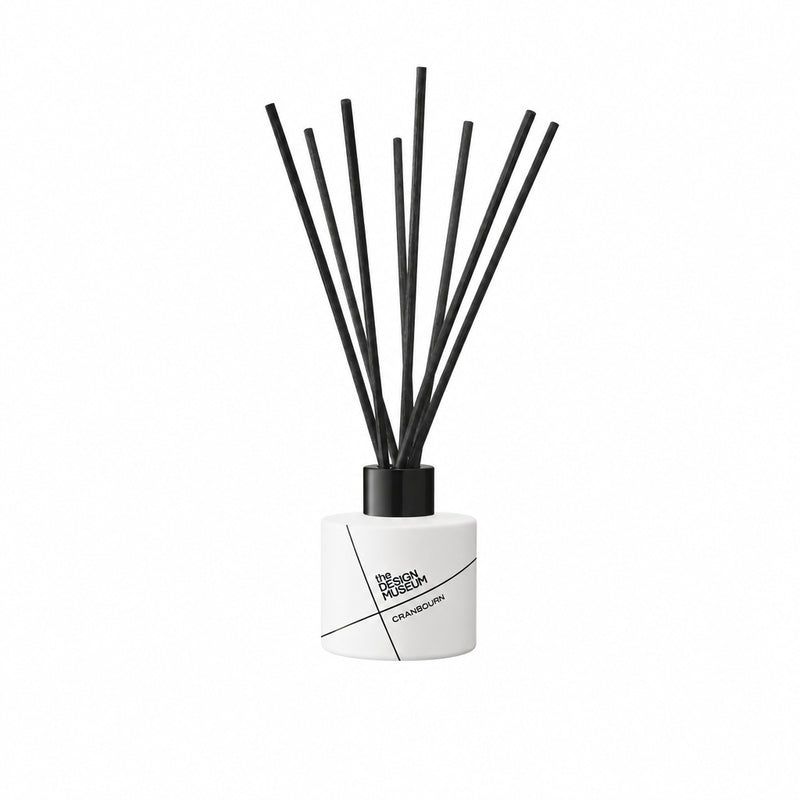 A yellow reed diffuser bottle with black diffuser sticks, shown on a clean light gray background.