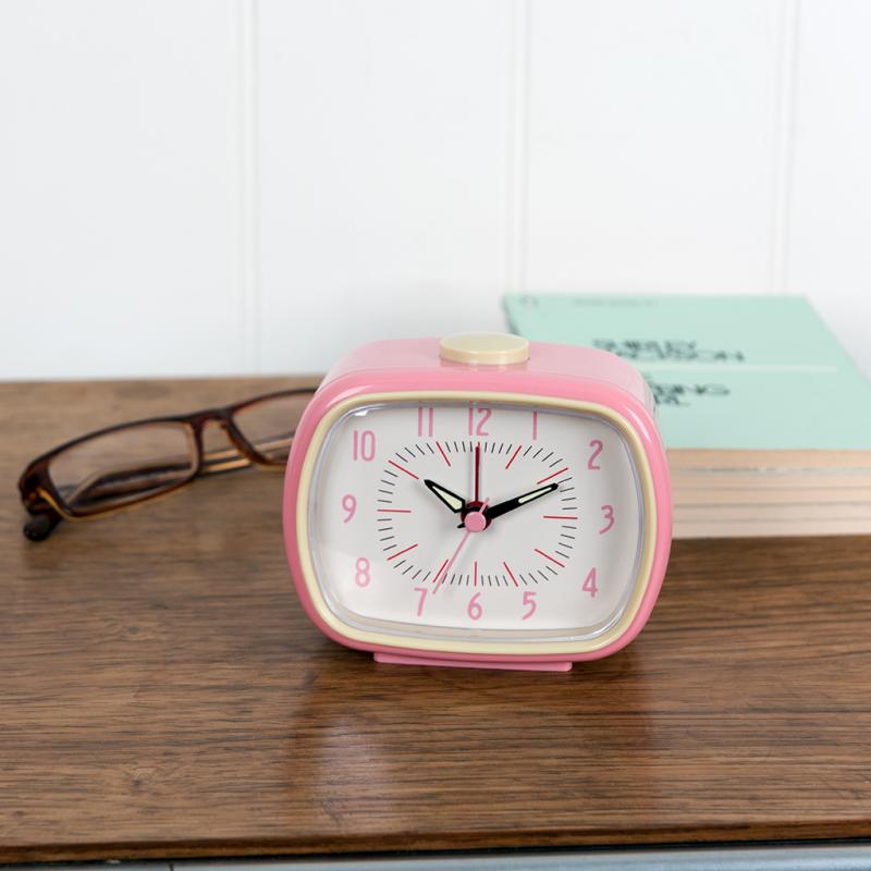 pink alarm clock on a wooden desk