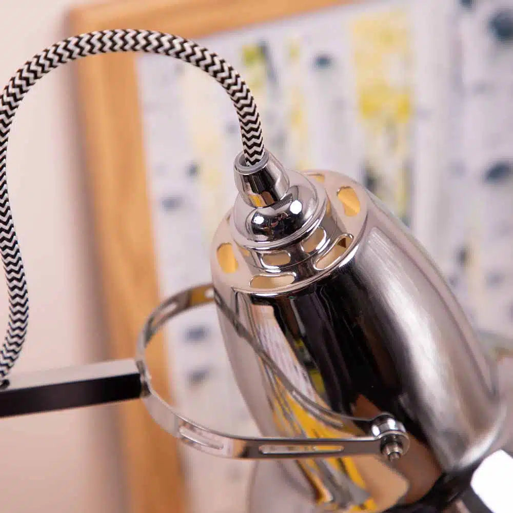 Close-up of a chrome lamp with a black and white striped cord against a blurred background