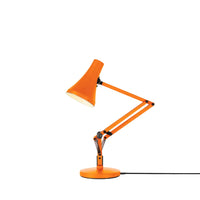 Orange desk lamp with adjustable arm on a white background