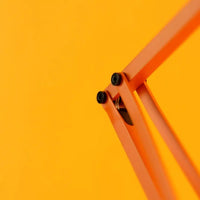 Orange metal desk lamp hinge on a yellow background