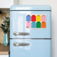 A pastel blue retro-style refrigerator in a kitchen setting, featuring a colorful weekly planner magnet on the upper door. 