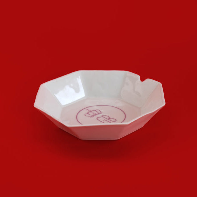 White trinket tray with a logo on a red background