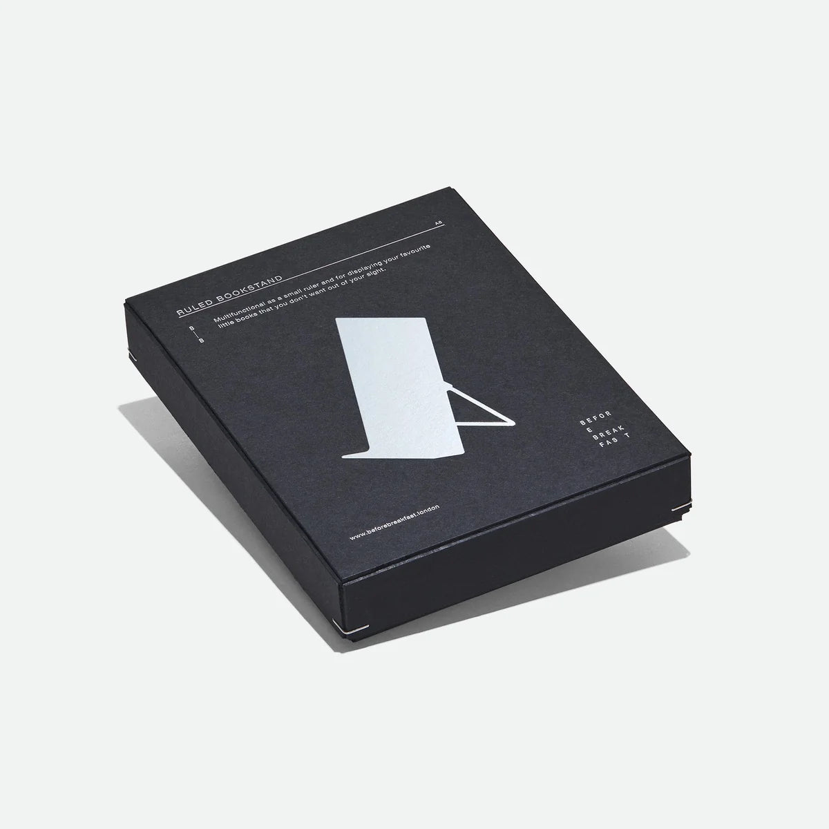 A black rectangular product box for a metal bookstand, photographed on a clean light gray background.