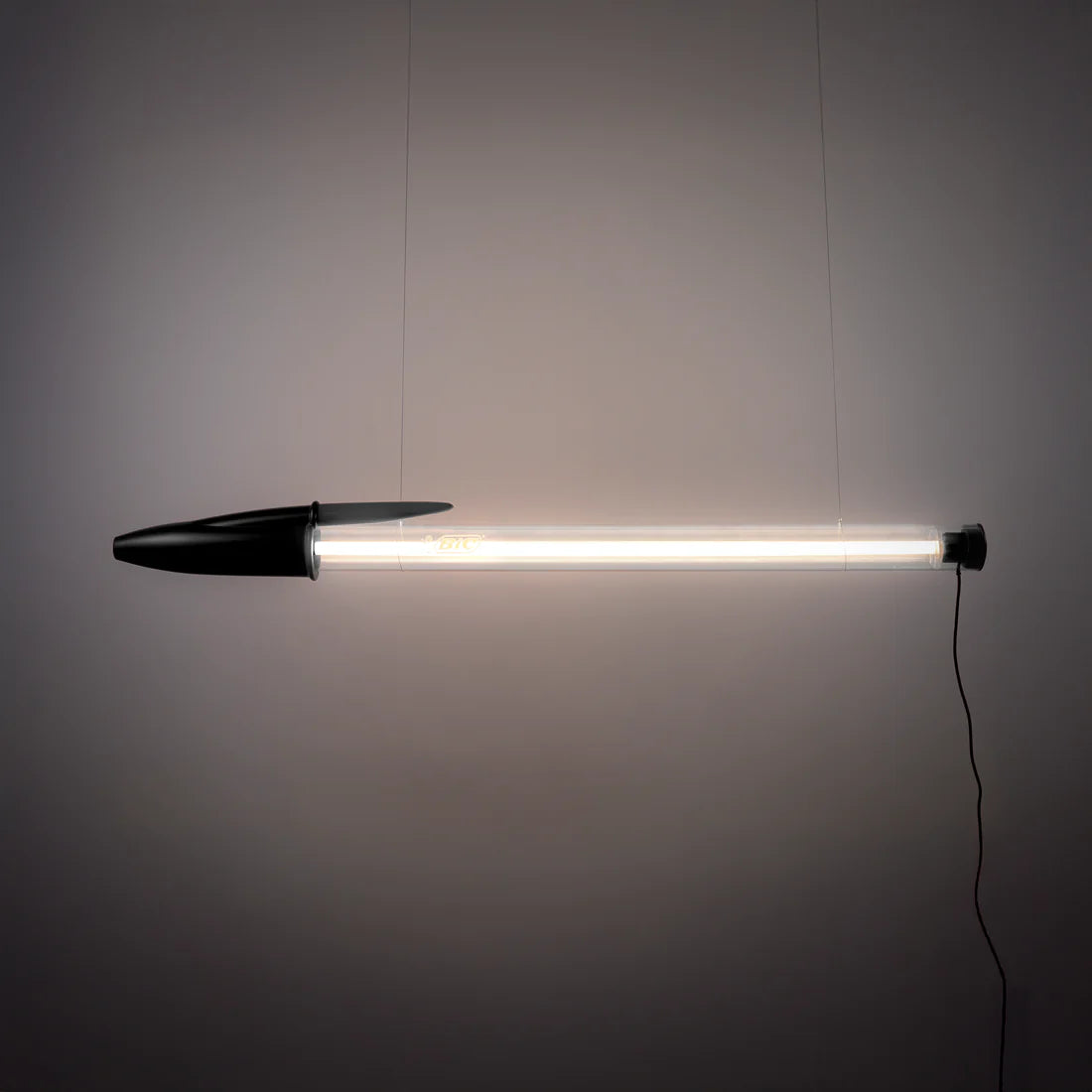 Black BIC pen lamp hanging against a grey wall.