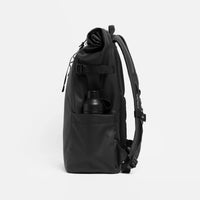 A black roll-top backpack shown from the side, featuring a side pocket with a black bottle tucked inside, on a light gray background.
