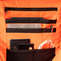 Close-up of a bright orange backpack organizer pocket holding various items in different pockets.