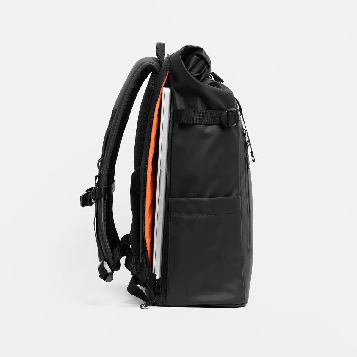 A black backpack shown from the side, with a silver laptop tucked inside a compartment against a light gray background.