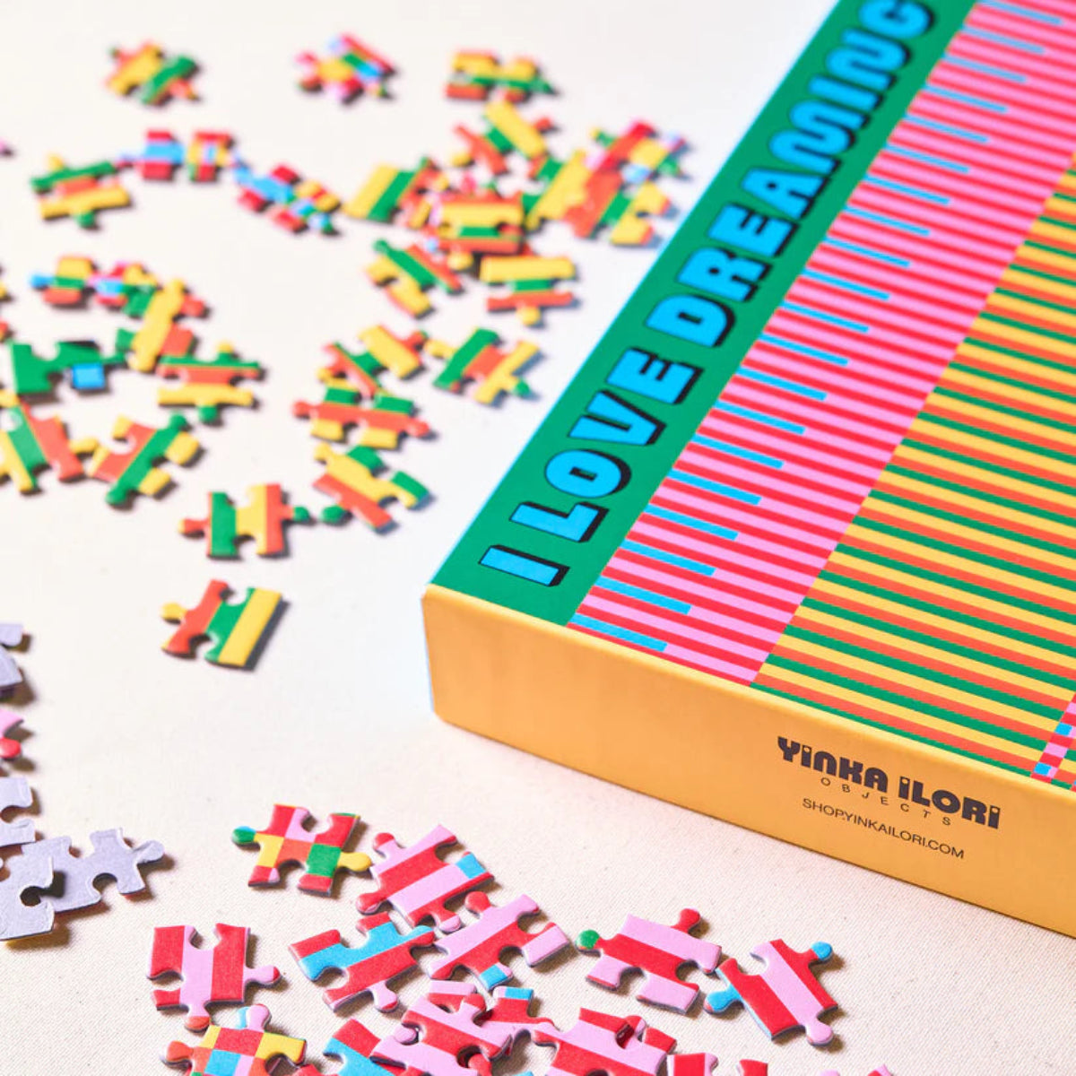 Puzzle with colorful pieces and a box labeled 'I Love Dreaming' by Yinka Ilori on a light background.