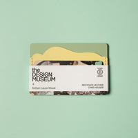 Green and yellow leather card holder with white packaging strip on a light green background