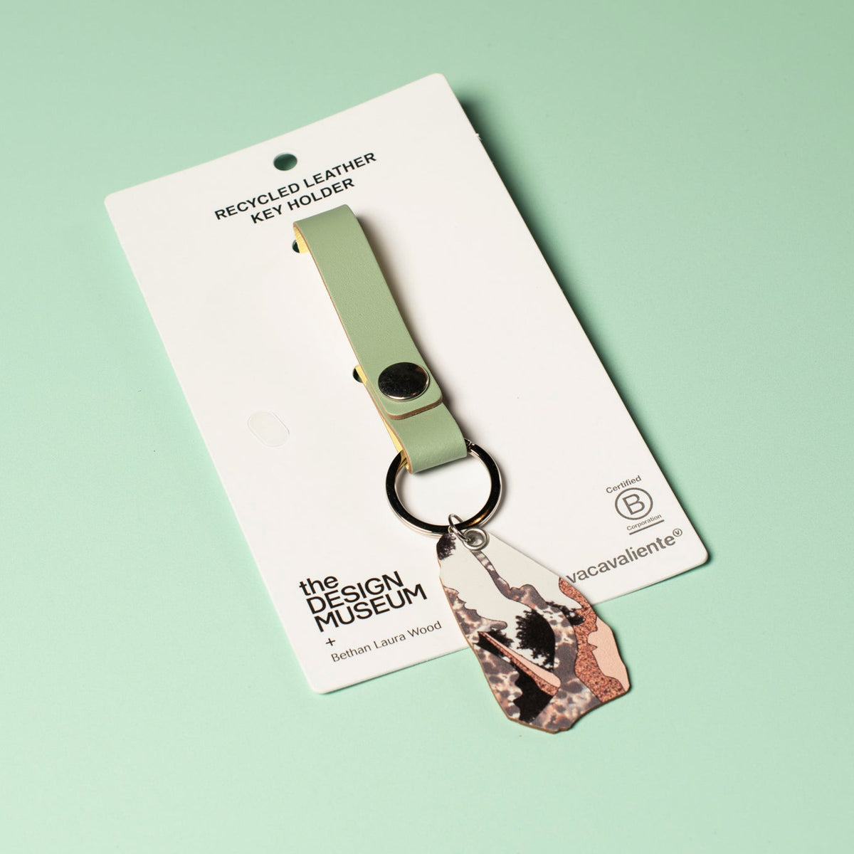 A green and pink abstract recycled leather keyring on a white card against a light green background