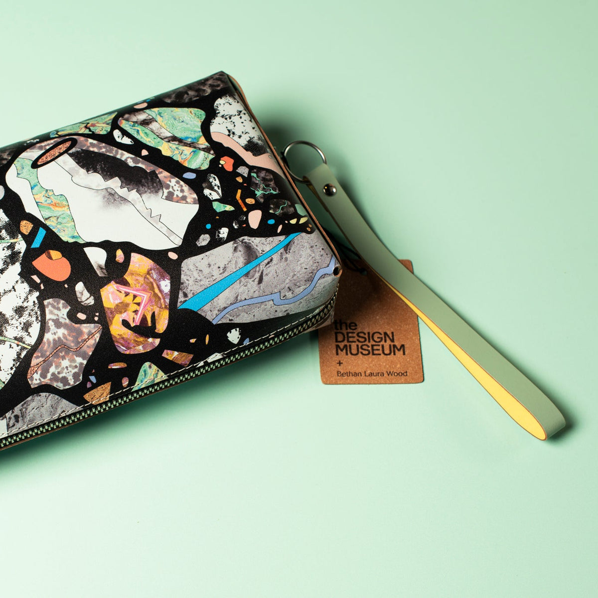 Multicolored abstract patterned zip pouch on a light green background.