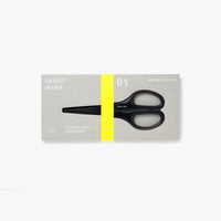 A pair of black scissors in a grey rectangular packaging box with neon yellow accents.