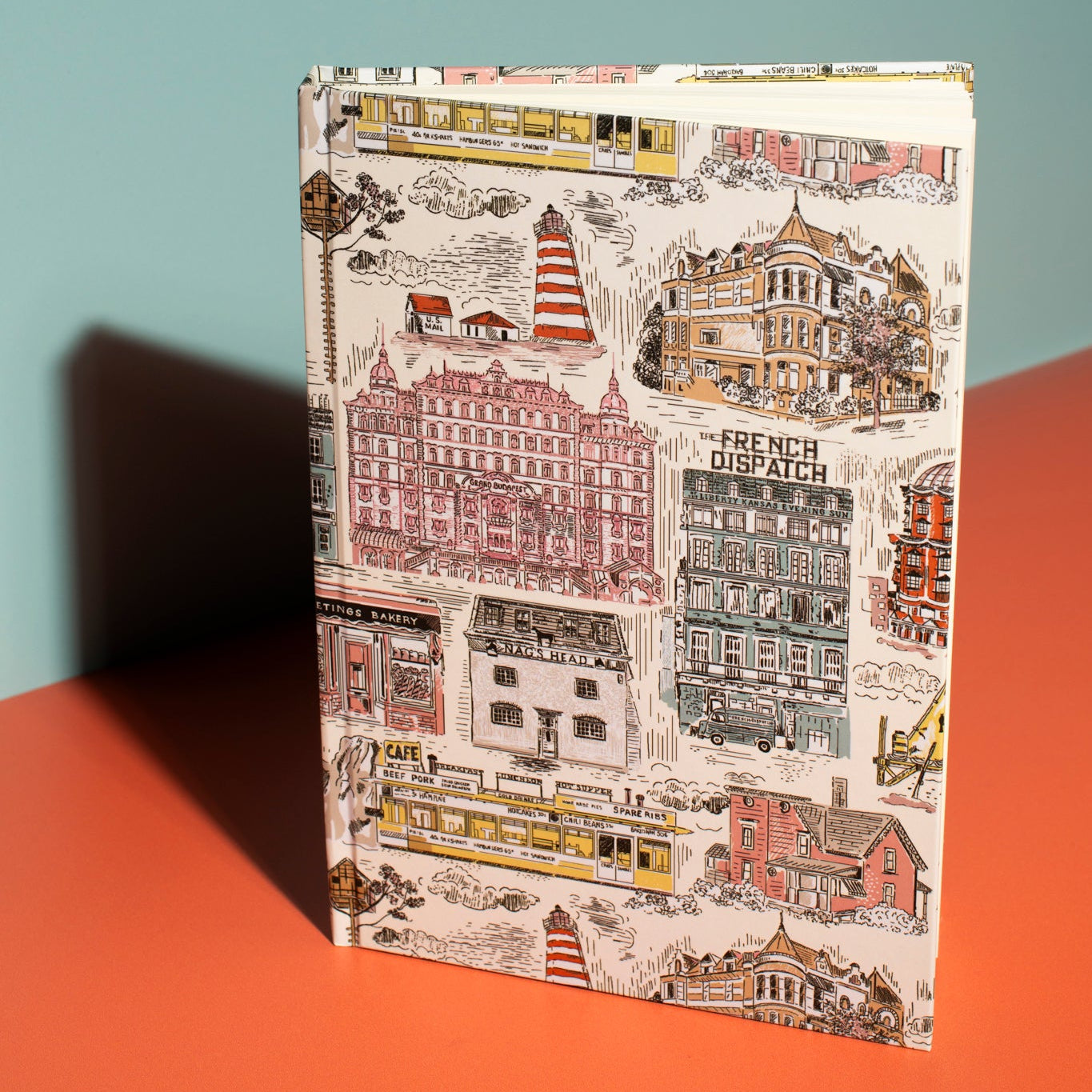 Notebook with cityscape design on a red surface and light blue background