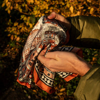 A person holding a scarf with architectural illustrations with leaves in the background