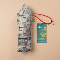 Folded white umbrella with building illustrations on a beige background