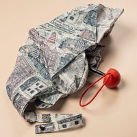 Folded white umbrella with building illustrations on a beige background