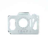 A silver metal camera-shaped multi tool with 13 different functions on a white background.
