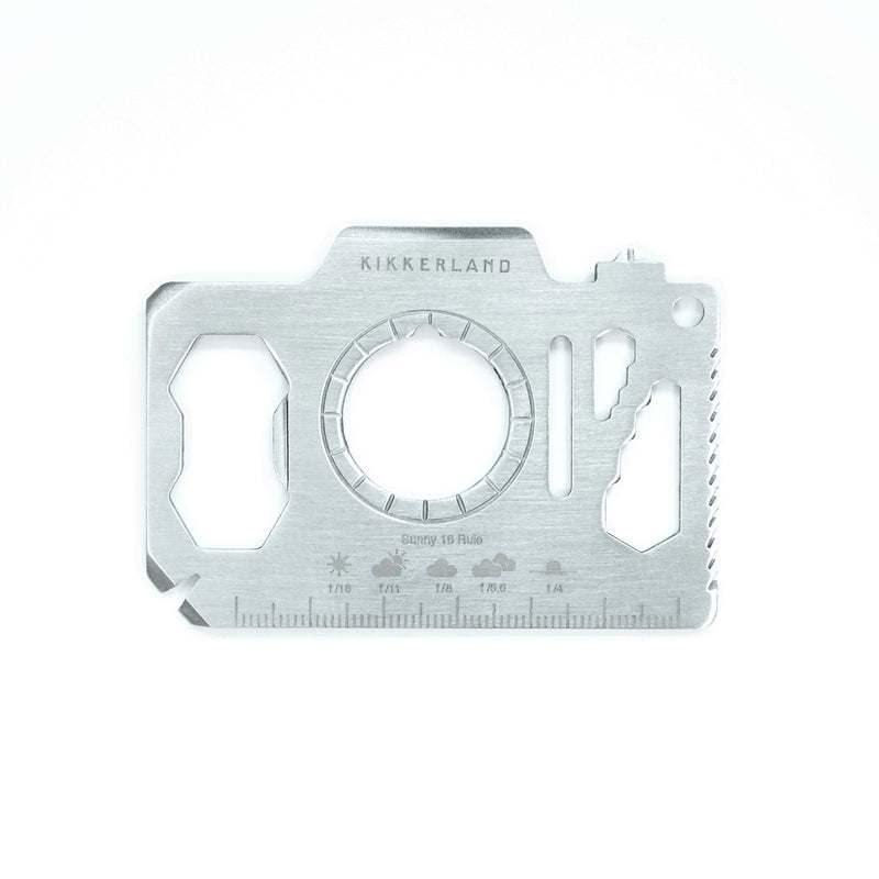 A silver metal camera-shaped multi tool with 13 different functions on a white background.