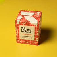 Orange grid design packaging box for the Design Museum candle on a yellow background. 