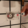 Person holding a cassette tape against a tiled wall with a grid pattern